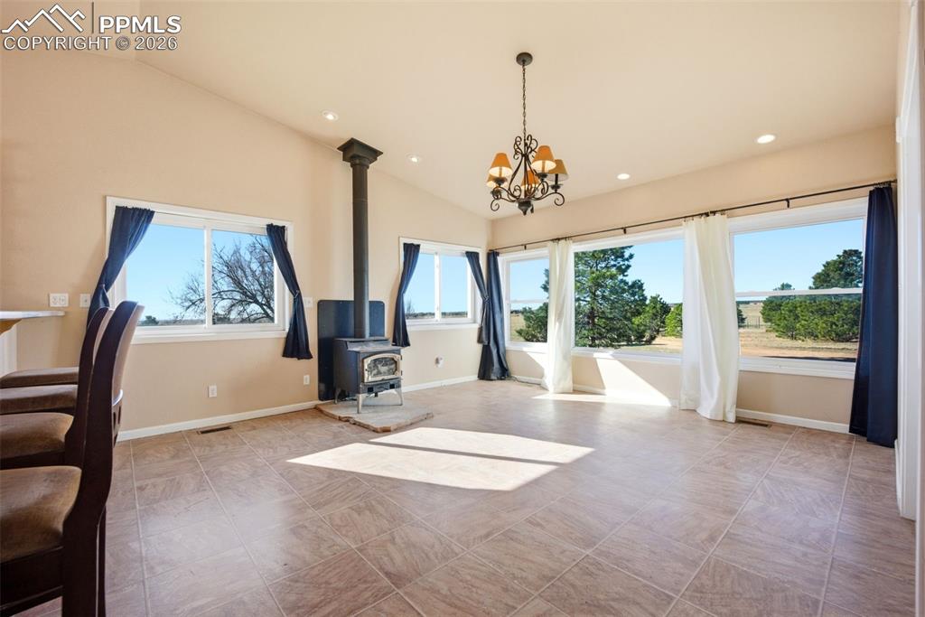 Dining area with lofted ceiling, hanging lights, and a wood stove
