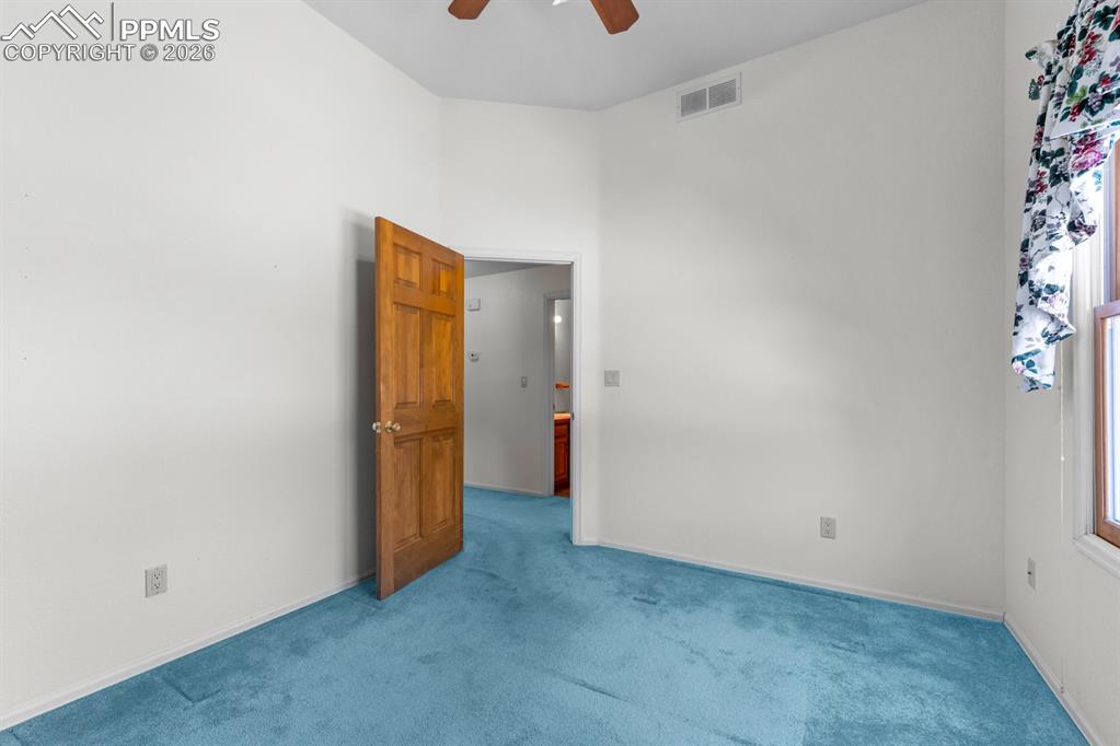 Carpeted empty room with ceiling fan and a high ceiling