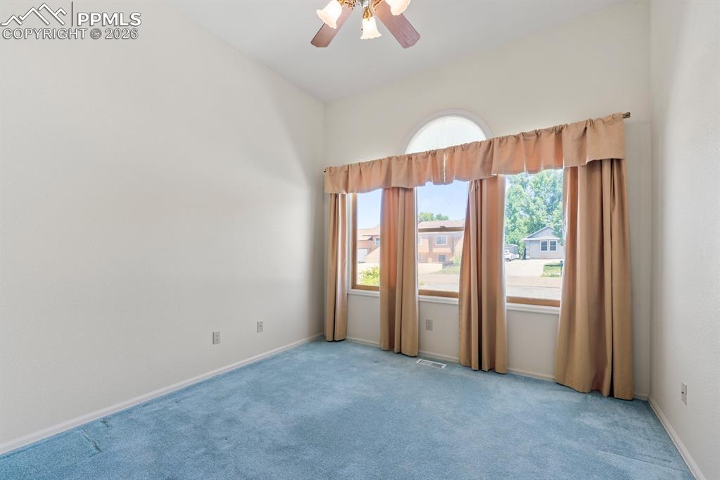 Carpeted spare room featuring a ceiling fan and baseboards