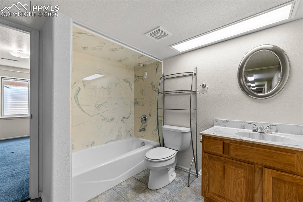 Full bath featuring a textured wall, vanity, bathing tub / shower combination, and a textured ceiling