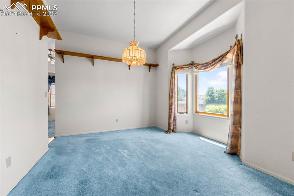 Carpeted empty room featuring baseboards and hanging lights