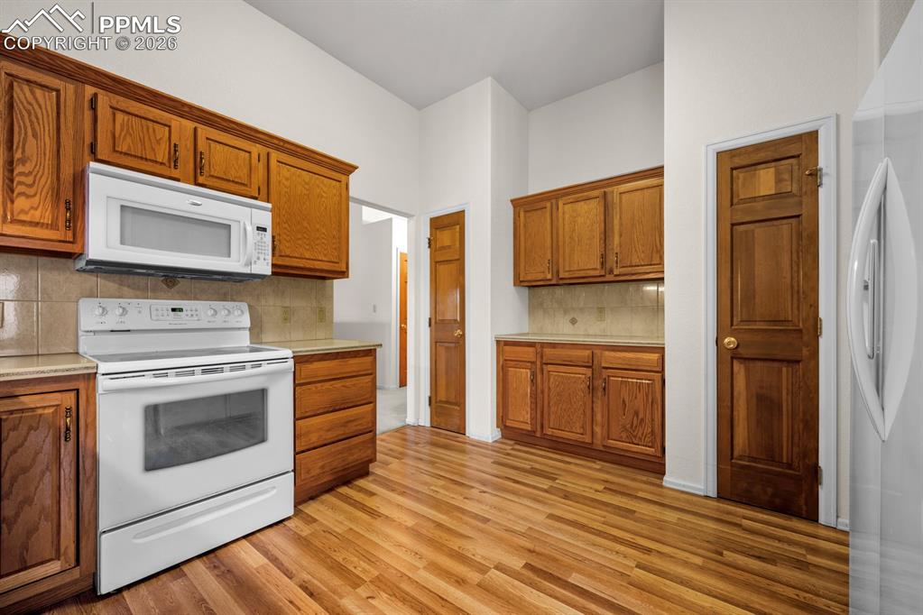 Kitchen featuring white appliances, light countertops, and wood finish cabinetry