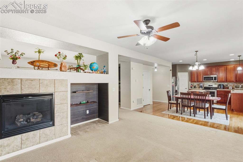 Living room with a chandelier, a tile fireplace, recessed lighting, ceiling fan, and built in shelves