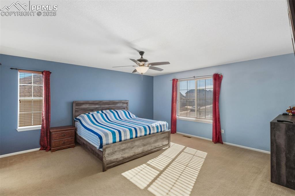 Bedroom with ceiling fan and light carpet