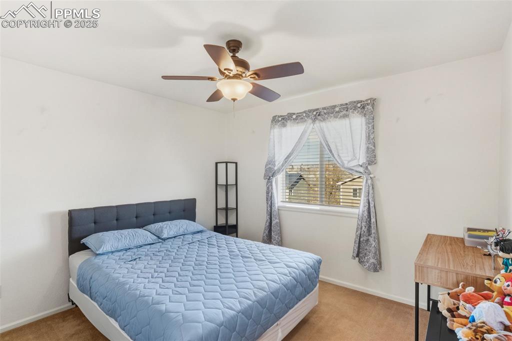 Carpeted bedroom featuring baseboards and a ceiling fan