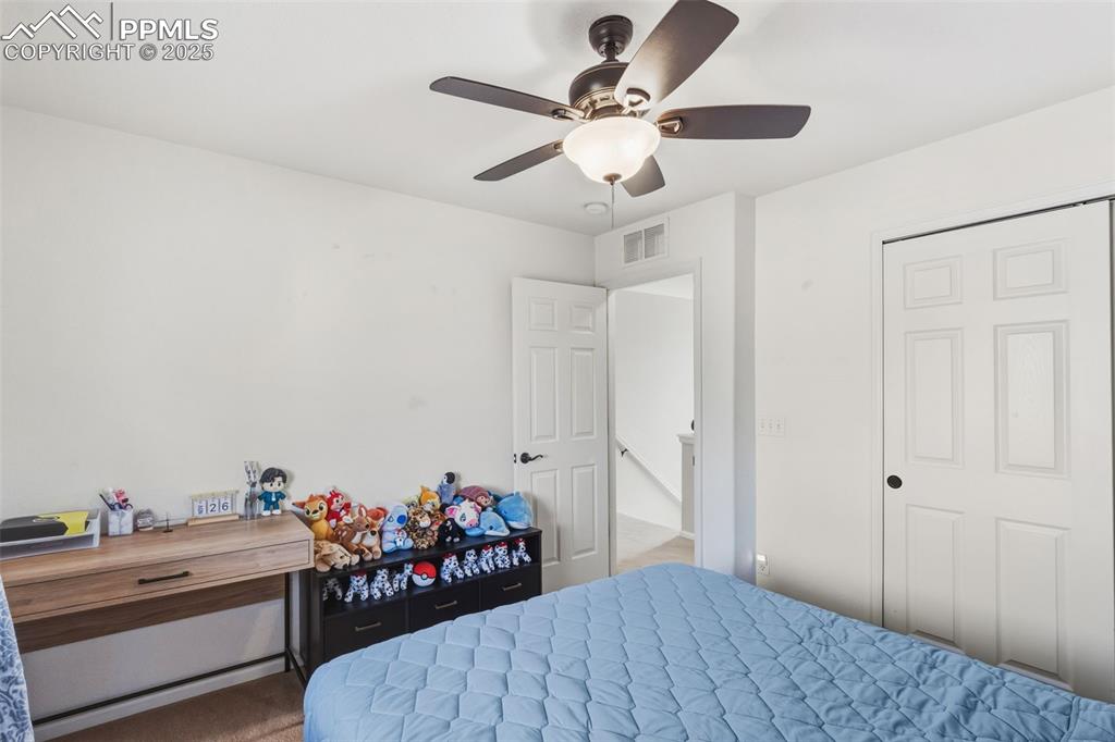 Carpeted bedroom featuring a ceiling fan and a closet