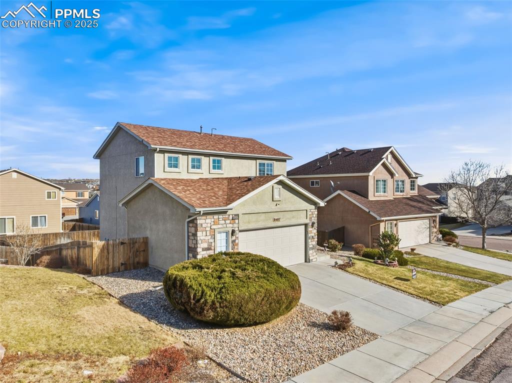 Traditional home with stone siding, driveway, stucco siding, a residential view, and roof with shingles