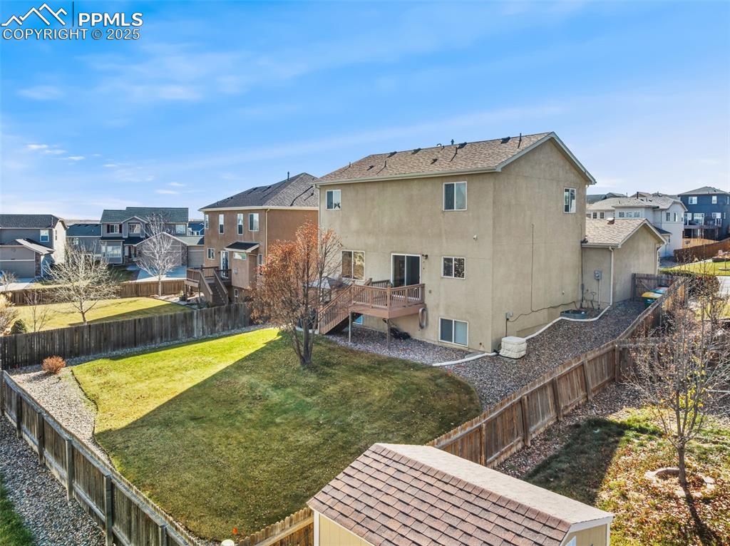 Back of house with a wooden deck, a residential view, stucco siding, a fenced backyard, and stairway