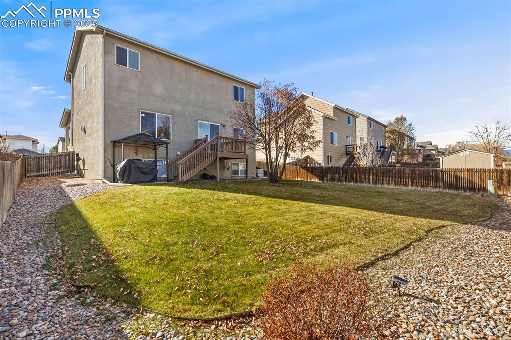 Back of property with a fenced backyard, a deck, stucco siding, and stairway