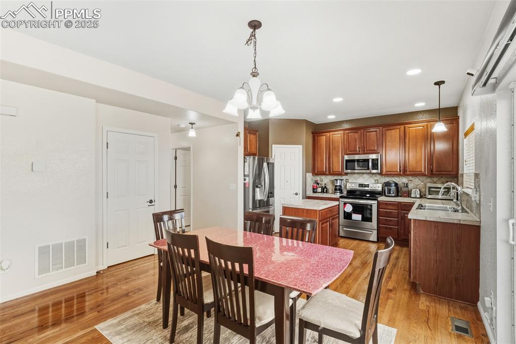 Kitchen with decorative light fixtures, light countertops, stainless steel appliances, a center island, and recessed lighting