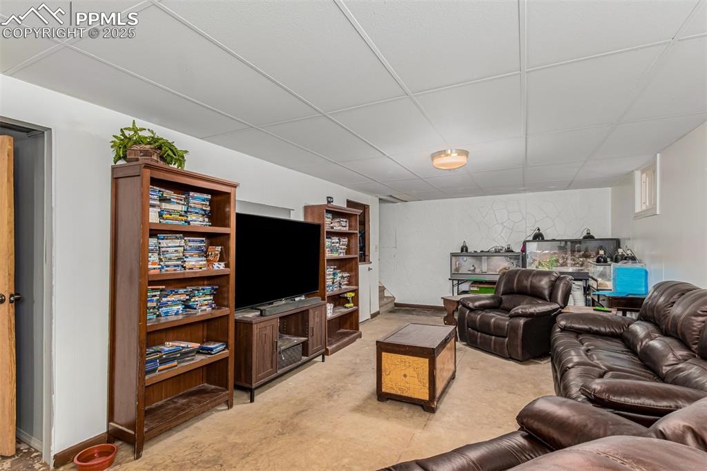 Living area with a paneled ceiling and concrete floors