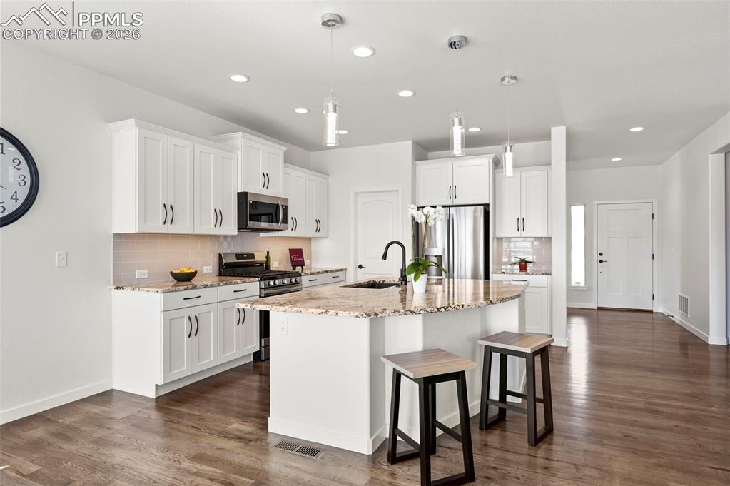 Kitchen featuring appliances with stainless steel finishes, tasteful backsplash, a breakfast bar area, an island with sink, and recessed lighting