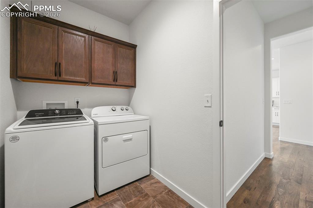 Laundry room featuring independent washer and dryer, cabinet space, and dark wood-type flooring