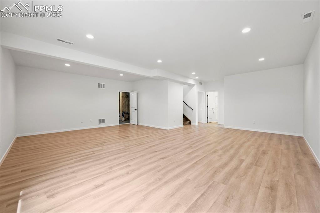 Unfurnished living room with stairs, recessed lighting, and light wood finished floors