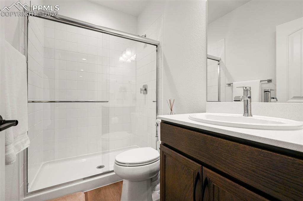 Full bath with a shower stall, vanity, and wood finished floors