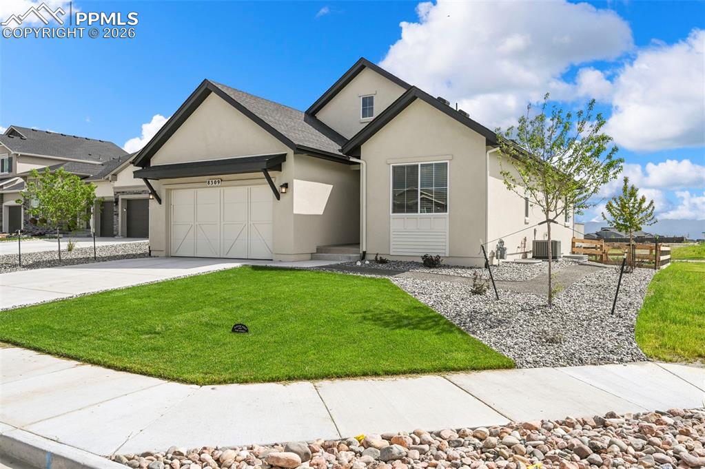View of front of property featuring a garage, stucco siding, concrete driveway, and a front yard