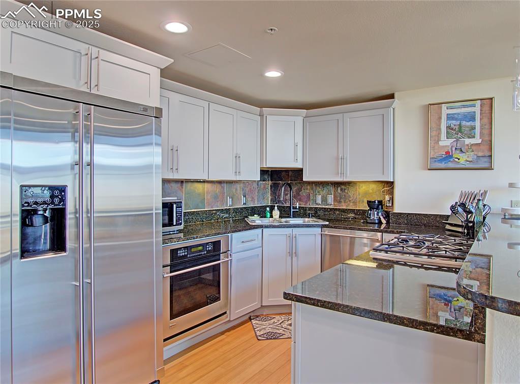 Kitchen with appliances with stainless steel finishes, dark stone counters, white cabinetry, and recessed lighting