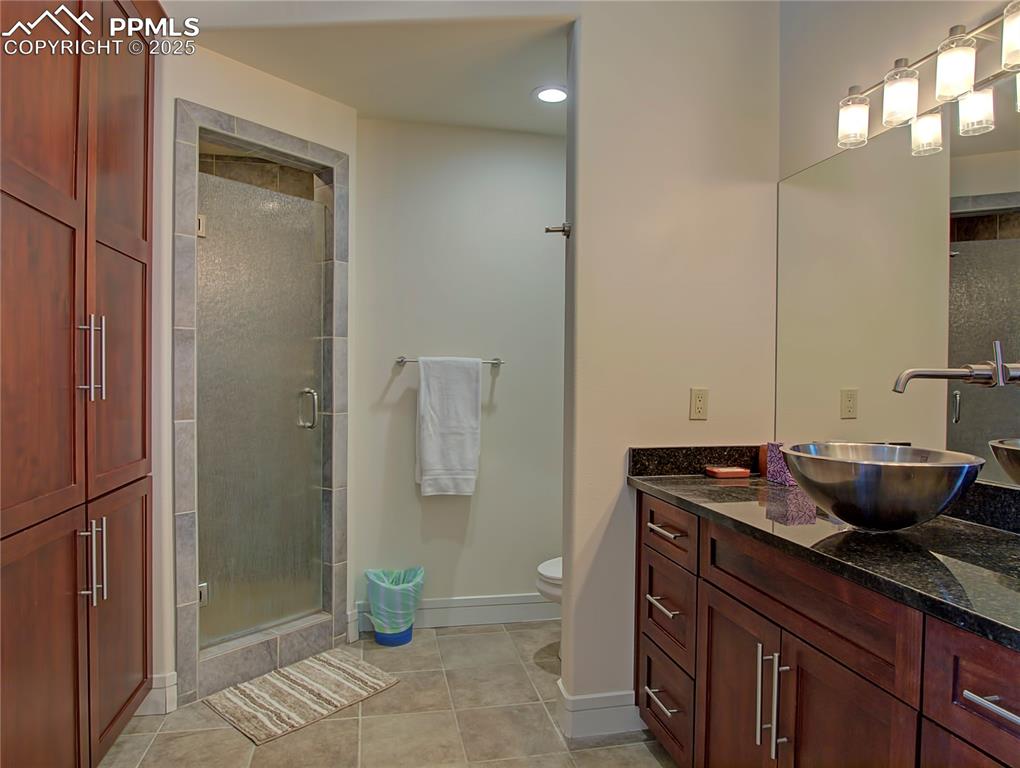 Full bathroom featuring light tile patterned floors, vanity, and a shower stall
