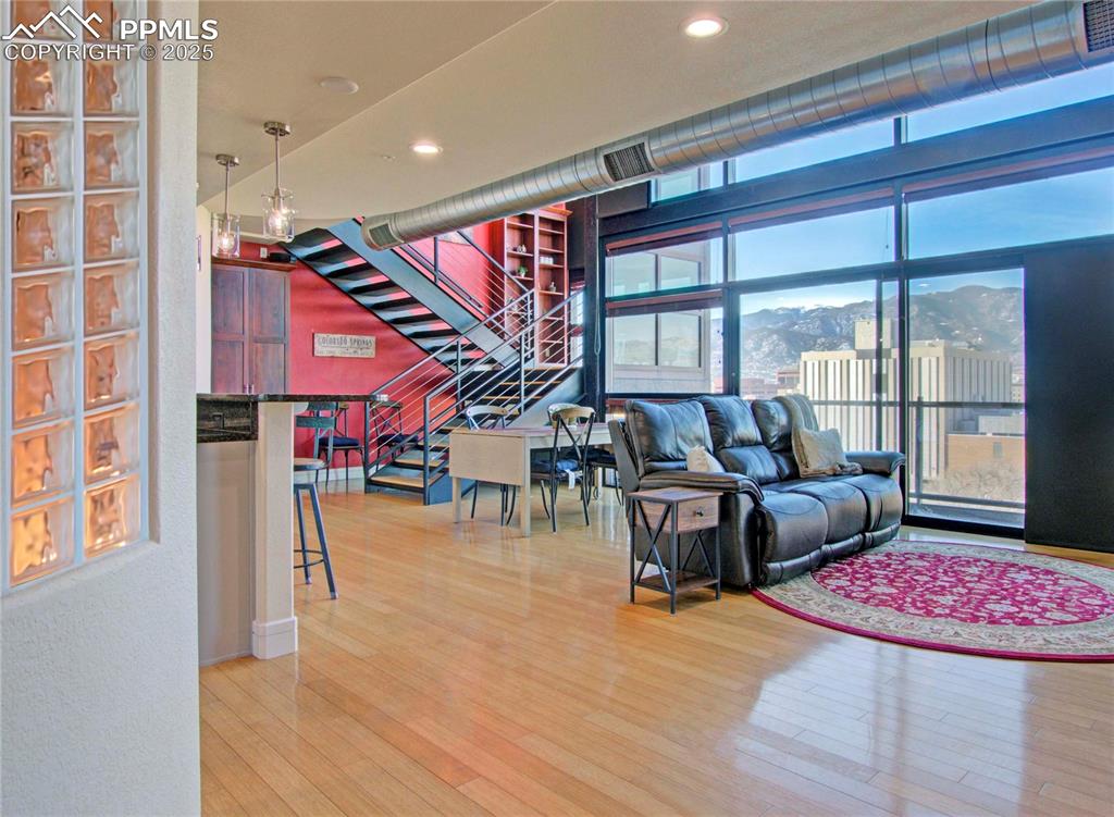 Living area featuring a mountain view, light wood-style flooring, stairway, expansive windows, and recessed lighting