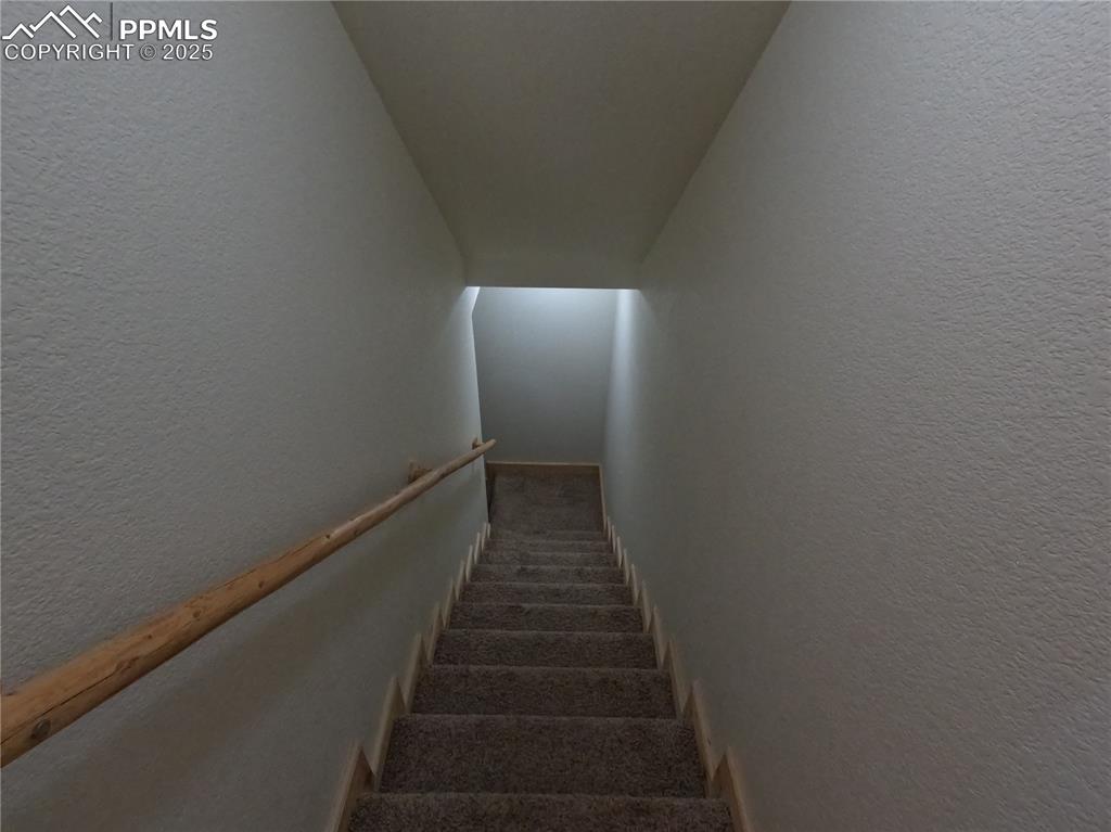 Staircase featuring a textured wall and carpet floors