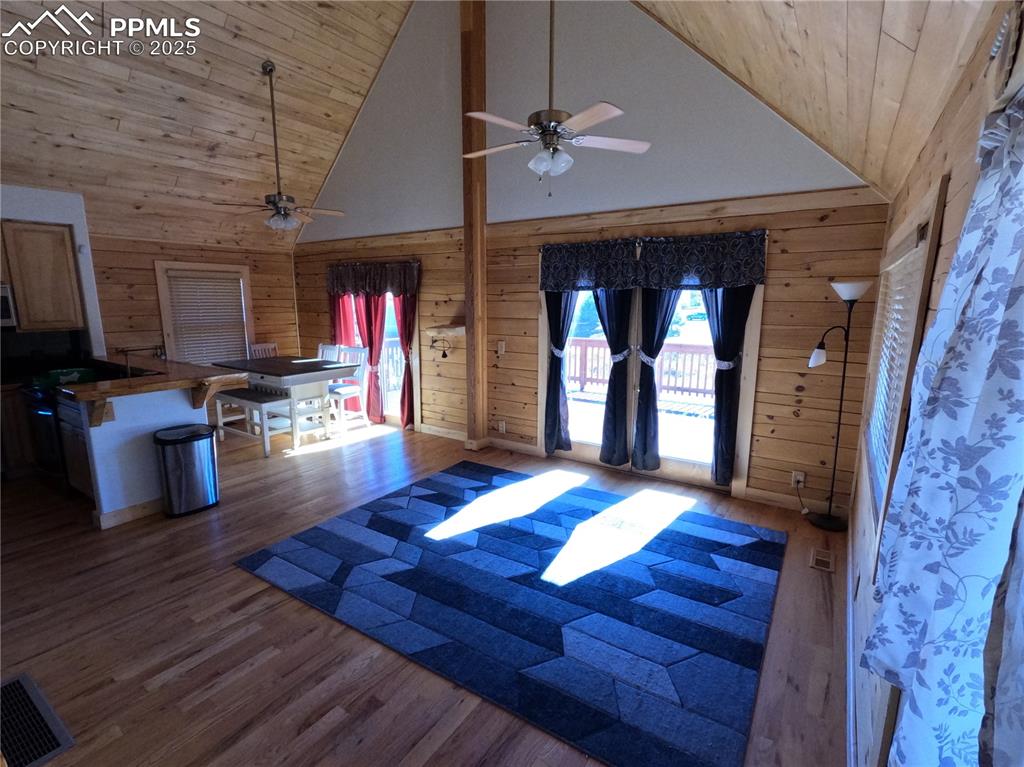 Foyer entrance with high vaulted ceiling, wood walls, dark wood finished floors, and wood ceiling