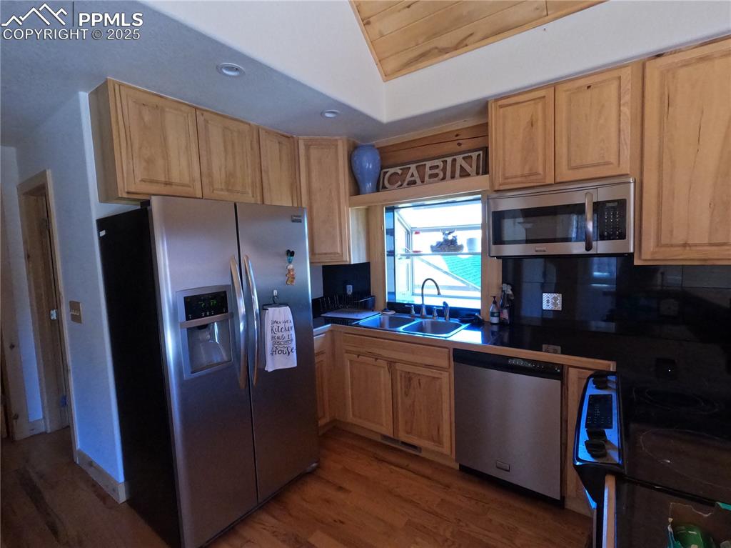 Kitchen with appliances with stainless steel finishes, dark wood-style flooring, dark countertops, recessed lighting, and tasteful backsplash