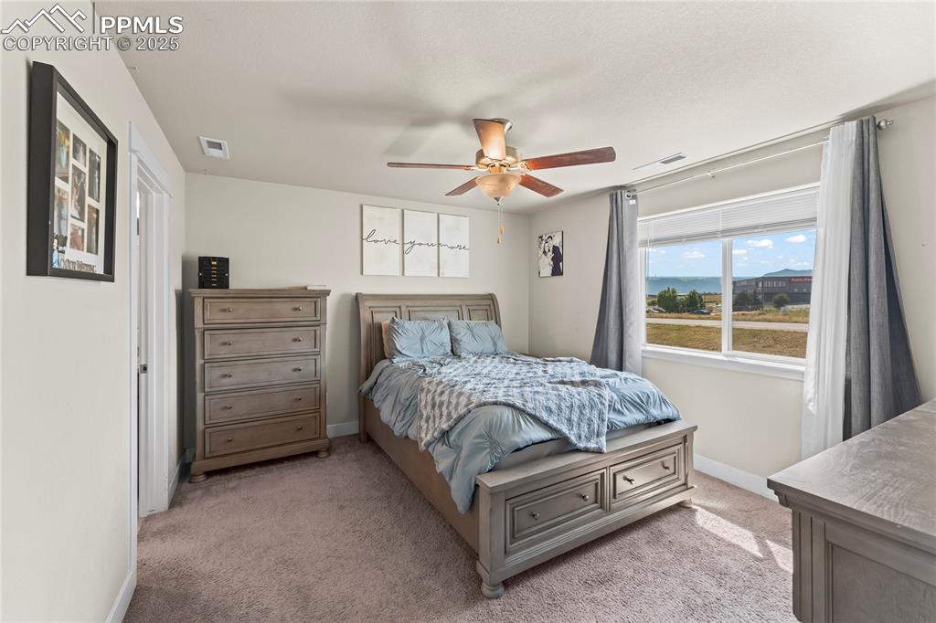 Bedroom with light colored carpet and a ceiling fan