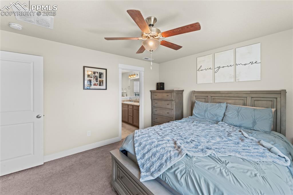 Bedroom featuring light carpet, ceiling fan, and ensuite bath
