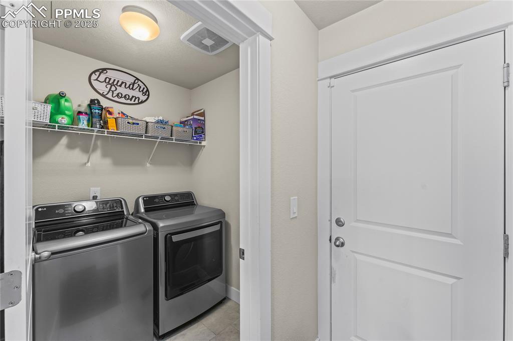 Laundry area with washer and clothes dryer and light tile patterned flooring