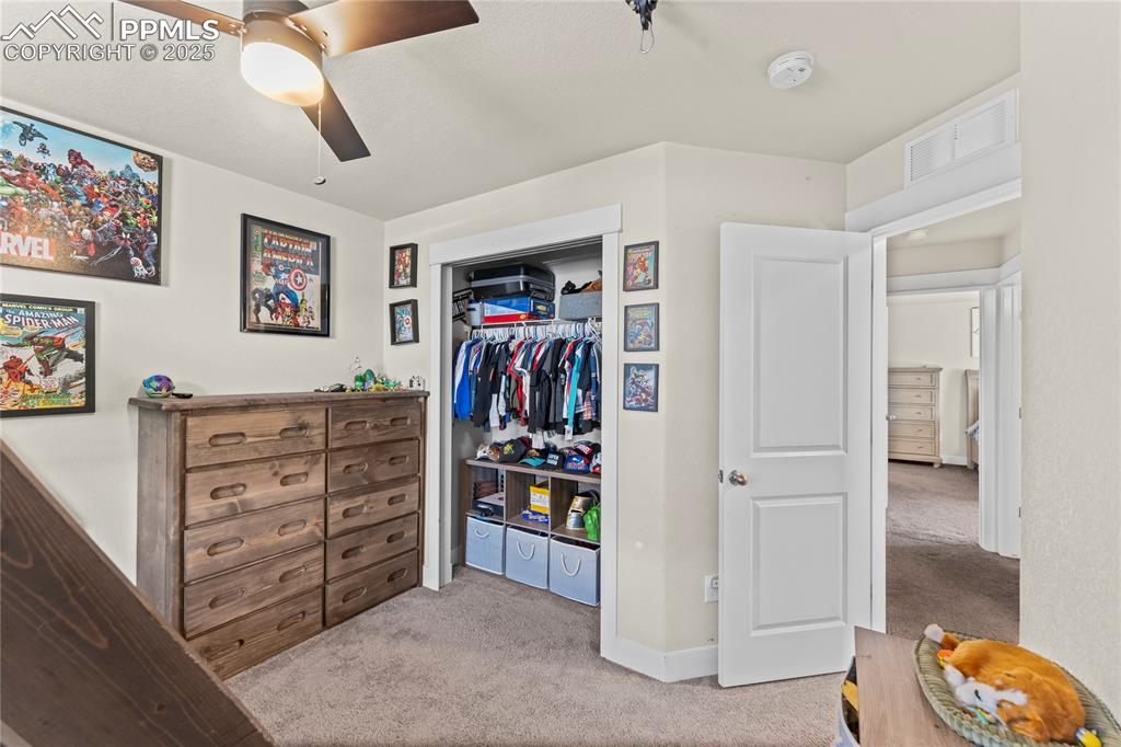 Bedroom with light carpet, a closet, and a ceiling fan