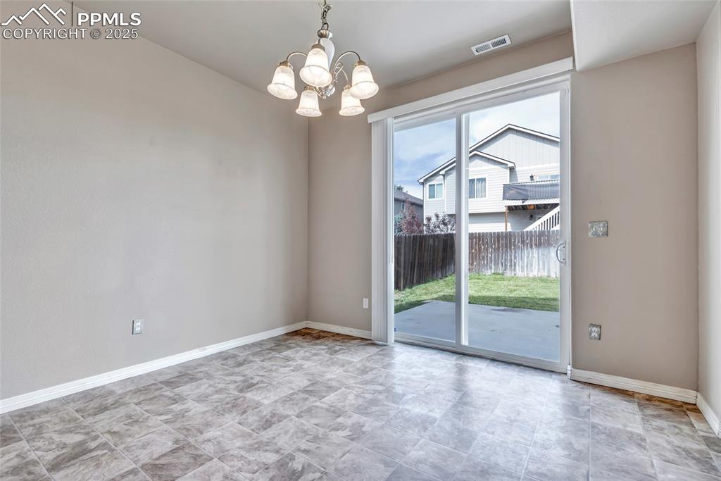 Unfurnished dining area featuring baseboards and a chandelier