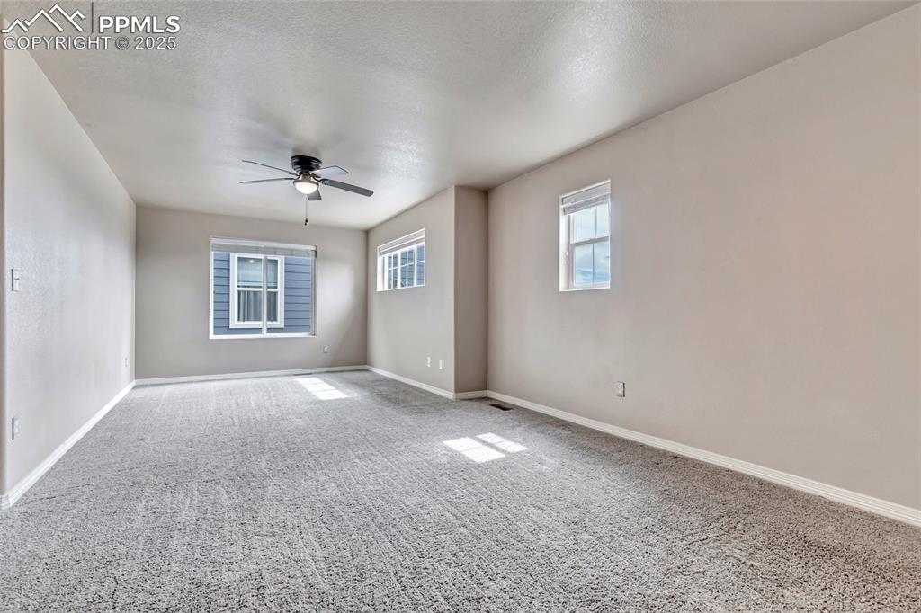 Empty room with carpet floors, a ceiling fan, and a textured ceiling