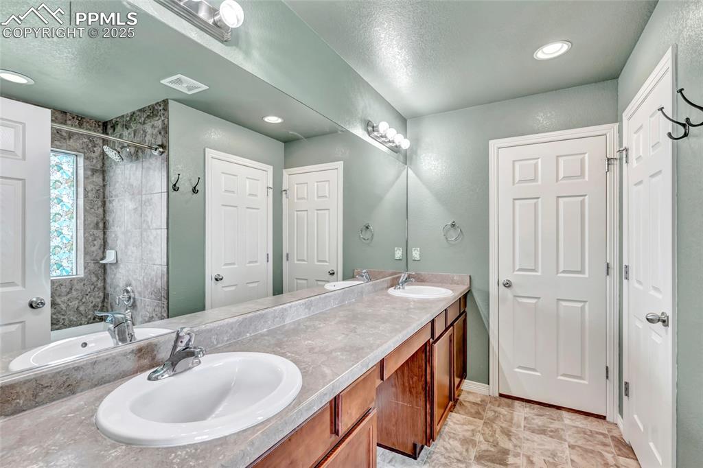 Full master bathroom featuring double vanity and a textured ceiling