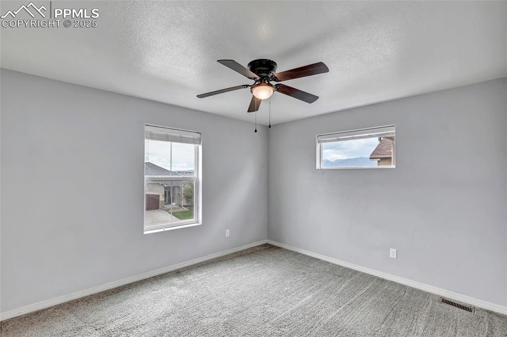 Secondary bedroom with a textured ceiling and ceiling fan
