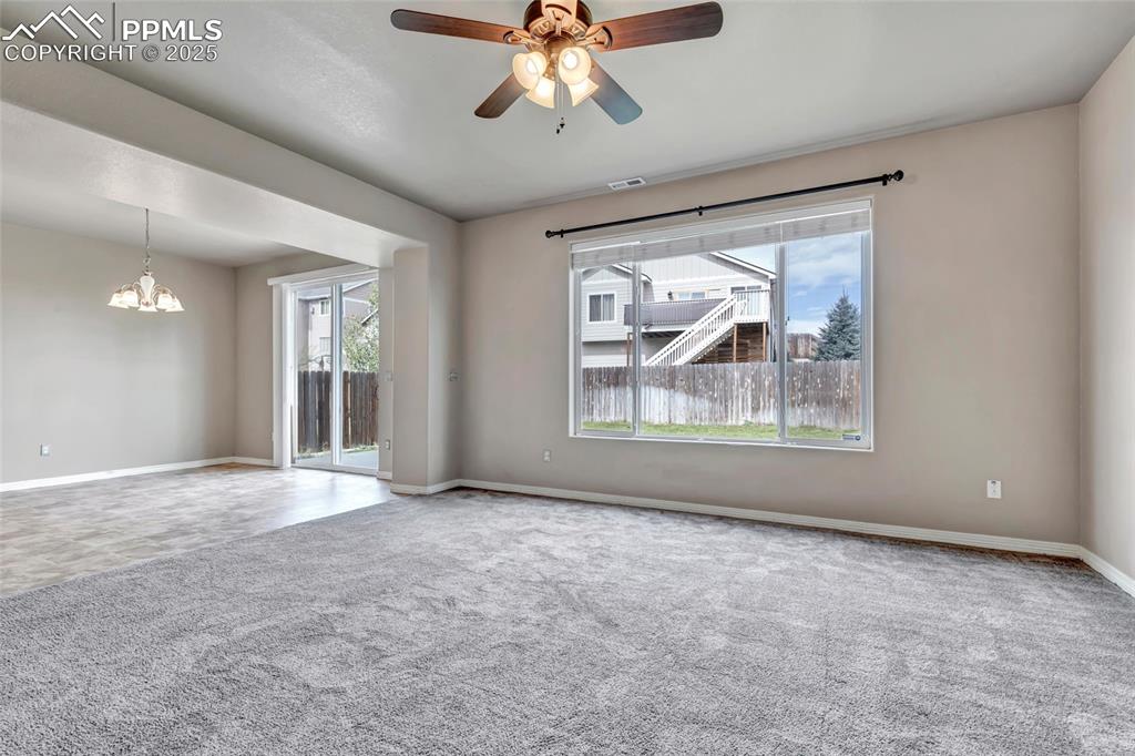 Spare room featuring plenty of natural light, carpet flooring, a ceiling fan, and a chandelier