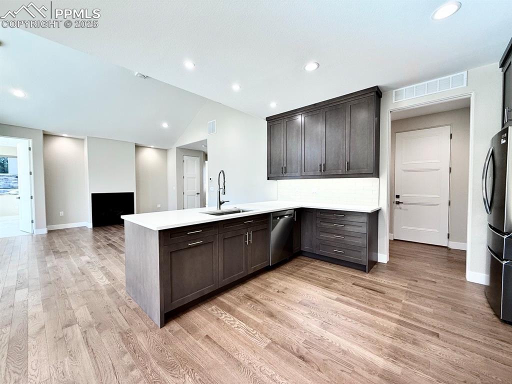 Full-sized Gourmet Kitchen with Quartz Countertops, Induction Range, Cabinetry to the Ceiling, Under-cabinet Lighting, Included Stainless Steel Fridge, and Wood Flooring.