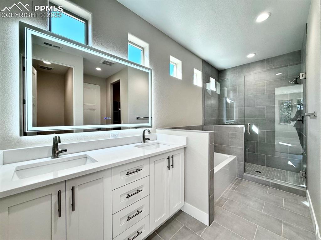 Luxurious Primary Bathroom with Double Vanities, Quartz Countertops, Heated Mirror to avoid Fogging, Deep Soaking Tub, Large Shower with Bench and Glass Door.