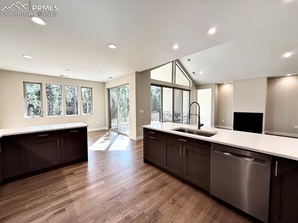 Full-sized Gourmet Kitchen with Quartz Countertops, Induction Range, Cabinetry to the Ceiling, Under-cabinet Lighting, Included Stainless Steel Fridge, and Wood Flooring.